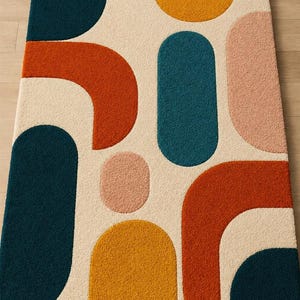 Puede incluir: Una alfombra rectangular con fondo color crema y un patrón de formas geométricas en azul cerceta, naranja quemado, amarillo mostaza y rosa suave. El diseño consta de varios rectángulos redondeados, arcos y círculos con una textura afelpada.