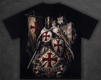 May include: A black t-shirt featuring a graphic print of a medieval knight in armor with a red cross emblem, holding a sword and shield. A banner with a red cross, a stone castle, and a scroll with the text DEUS VULT are also depicted.