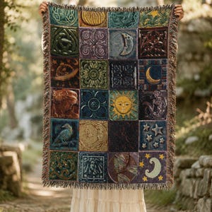 May include: A rectangular woven throw blanket featuring a grid of twenty square panels with celestial, floral, and animal motifs in shades of blue, green, purple, and gold. The blanket has a fringed edge and displays sun, moon, and star designs.