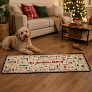Puede incluir: Una alfombra rectangular de fondo crema con un patr&oacute;n navide&ntilde;o repetitivo de lazos rojos, &aacute;rboles verdes y cajas de regalo. El texto THE JOHNSON FAMILY est&aacute; centrado, rodeado por los nombres Emily, Anna y Sophia en diversas tipograf&iacute;as.