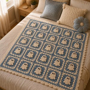 May include: A crochet blanket featuring a repeating pattern of square motifs, each containing a small white ghost with black eyes. The blanket is bordered with a scalloped cream-colored edge and constructed from alternating blue and cream yarn squares.
