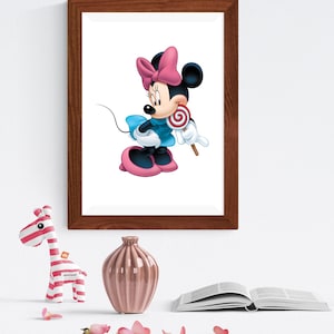 May include: A framed wall art print featuring a cartoon mouse character with black ears, a pink bow, and a blue dress, holding a red and white swirled lollipop. The artwork is displayed in a dark brown wooden frame on a plain white wall.