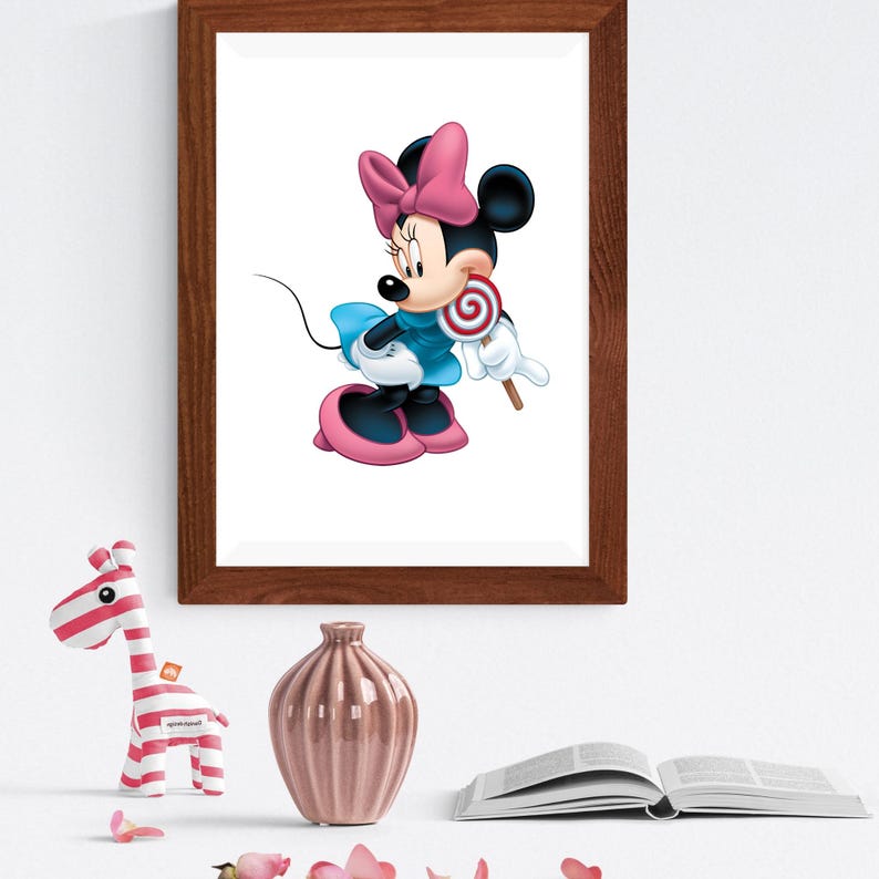 May include: A framed wall art print featuring a cartoon mouse character with black ears, a pink bow, and a blue dress, holding a red and white swirled lollipop. The artwork is displayed in a dark brown wooden frame on a plain white wall.