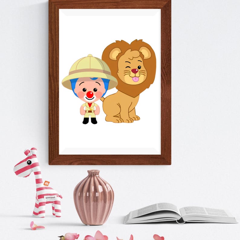 May include: A framed wall art print featuring a cartoon explorer with blue hair and a red nose wearing a tan safari hat and outfit, standing next to a winking lion with its tongue out. The frame is dark brown wood with a simple rectangular design.