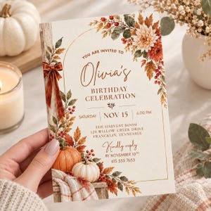 May include: A rectangular birthday invitation card featuring an arched gold frame, autumn foliage, red berries, and pumpkins. The text reads: You are invited to Olivia's Birthday Celebration, Saturday Nov 15, 6.00 PM, The Harvest Room, 128 Willow Creek Drive, Francklin, Tennessee, Kindly reply by November 10th, 615 555 7653.