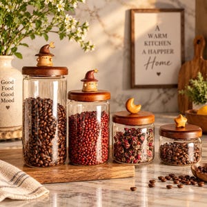 May include: Four clear glass storage jars with wooden lids. Two lids feature small brown wizard hat toppers, one has a crescent moon, and one has a star. The jars contain coffee beans, red beans, dried rose buds, and more coffee beans.