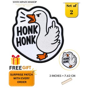 May include: An embroidered patch featuring a white goose with an orange beak and feet, displaying an angry expression while giving the middle finger. The text HONK HONK is in black, and a ruler shows the patch measures 7.62 cm or 3 inches.