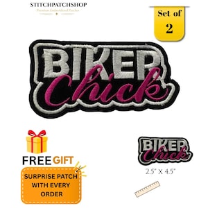 May include: A set of two embroidered patches featuring the text BIKER CHICK in white and pink thread on a black background with a white border. The patch measures 6.35 cm by 11.43 cm as indicated by a visible ruler in the image.
