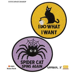 May include: Two circular embroidered patches, each 3 inches in diameter. One is yellow with a black cat knocking over a white mug, reading I DO WHAT I WANT. The other is lavender with a black spider-cat and web, reading SPIDER CAT SPINS AGAIN.