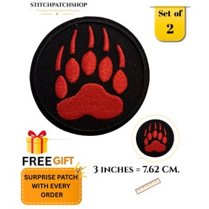Op de afbeelding: Een ronde geborduurde patch met een rode berenpootafdruk op een zwarte achtergrond. De patch heeft een diameter van 7,62 cm. De afbeelding bevat de tekst STITCHPATCHSHOP, Set of 2, en 3 INCHES = 7.62 CM, samen met een liniaalafbeelding.