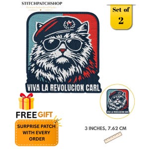 May include: A set of two embroidered patches featuring a cat wearing a beret and sunglasses, with the text VIVA LA REVOLUCION CARL. The patches measure 3 inches in width. A yellow gift box icon and text indicating a free surprise patch are included.