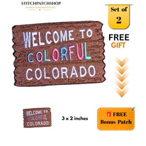 May include: A rectangular embroidered patch with a brown wood-grain texture background. The text reads WELCOME TO COLORFUL COLORADO in white, blue, pink, and teal thread. The patch measures 3 x 2 inches and is part of a set of two.