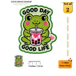 May include: An embroidered patch featuring a green frog holding a pink boba tea drink with black pearls. The text reads GOOD DAY GOOD LIFE. A ruler shows the patch is 3 inches wide. A smaller version of the patch is included as a bonus item.