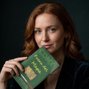 Può includere: Un libro verde intitolato CDMX Fuera del Mapa con testo giallo e verde e una piccola grafica a mappa rettangolare sulla copertina. Il libro è tenuto da una persona con capelli ramati ondulati che indossa un blazer di velluto scuro.