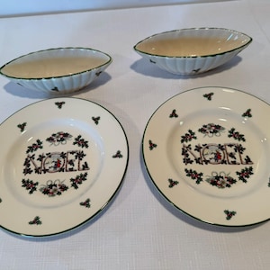 Peut inclure: Deux assiettes en céramique couleur crème et deux bols ovales assortis avec un bord vert et un motif central de feuilles de houx et de baies, avec le mot NOEL imprimé au centre. Les assiettes et les bols ont un bord festonné.