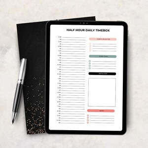 May include: A digital tablet displaying a Half Hour Daily Timebox planner template with a vertical schedule from 4 AM to 10 PM, sections for priorities, tasks, a brain dump, and notes, accompanied by a black and silver ballpoint pen.