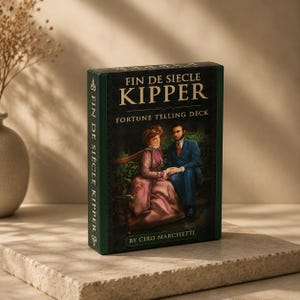 May include: A rectangular box for the Fin de Siecle Kipper fortune telling deck by Ciro Marchetti. The dark green box features an illustration of a person in a pink dress and a person in a blue suit sitting on a bench, with gold text.