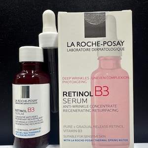 May include: A La Roche-Posay Retinol B3 serum bottle and its white cardboard packaging box. The bottle is dark red with a white label and a white dropper cap. The box is white with pink text and a graphic of the bottle, labeled 30ml.