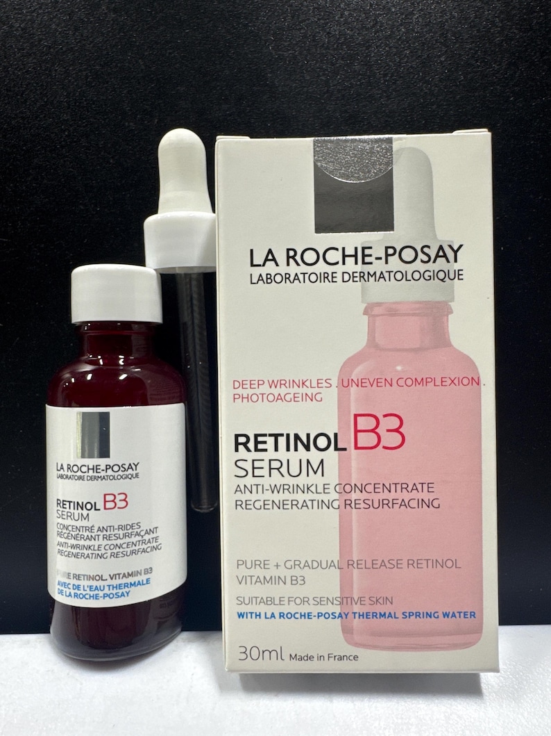 May include: A La Roche-Posay Retinol B3 serum bottle and its white cardboard packaging box. The bottle is dark red with a white label and a white dropper cap. The box is white with pink text and a graphic of the bottle, labeled 30ml.
