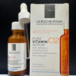 Könnte beinhalten: Eine 30 ml Braunglasflasche mit La Roche-Posay Pure Vitamin C12 Serum und weißem Tropfverschluss, begleitet von der rechteckigen weißen Pappschachtel mit orangefarbenem und schwarzem Text, der die Anti-Falten-Eigenschaften beschreibt.