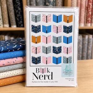 May include: A quilt pattern booklet titled Book Nerd by Angela Pingel Designs, featuring a grid of twenty illustrated open books in various colours and patterns. The cover displays the finished size as 54 inches by 66 inches on a white background.