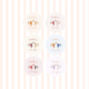 May include: Six circular stickers featuring vertical stripes and illustrations of two monkeys clinking glasses. Each sticker displays the text Cheers to the followed by a specific word: tigers, lids, noles, gators, dawgs, or tigers, in various colors.