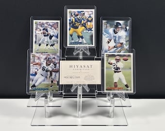 Könnte beinhalten: Ein mehrstufiger Präsentationsständer aus klarem Acryl mit vier Football-Sammelkarten und einer zentralen rechteckigen Karte mit dem Text HIYASAT EXHIBITION und HEX-NFL-003. Die Karten zeigen verschiedene Footballspieler in Aktion.