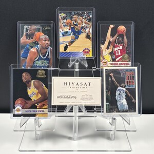 K&ouml;nnte beinhalten: Ein transparenter, mehrstufiger Acryl-Pr&auml;sentationsst&auml;nder mit f&uuml;nf Basketball-Sammelkarten und einer zentralen rechteckigen Karte mit der Aufschrift HIYASAT EXHIBITION HEX-NBA-006. Die Karten zeigen verschiedene Spieler in Aktion, darunter Vernon Maxwell, in Schutzh&uuml;llen.