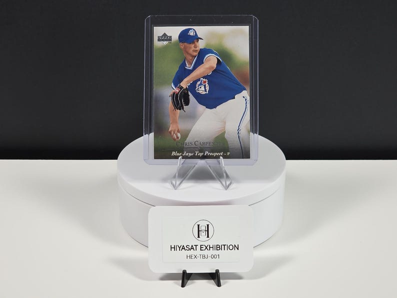 Puede incluir: Una tarjeta de b&eacute;isbol que muestra a Chris Carpenter con un uniforme azul de los Toronto Blue Jays, dentro de una funda de pl&aacute;stico transparente. El texto dice Chris Carpenter y Blue Jays Top Prospect. Un letrero blanco muestra HIYASAT EXHIBITION HEX-TBJ-001.