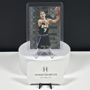 May include: A Bobby Hurley basketball trading card in a protective plastic sleeve, featuring the player in a black Kings jersey with the number 7. The card includes the text 'Special Edition' and is displayed with a Hiyasat Exhibition label.