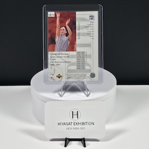 May include: A Bobby Hurley basketball trading card in a clear protective sleeve, featuring a photograph of the player shooting, career statistics, and the text Set NCAA Division I career assists record (1,076). Includes a Hiyasat Exhibition card.