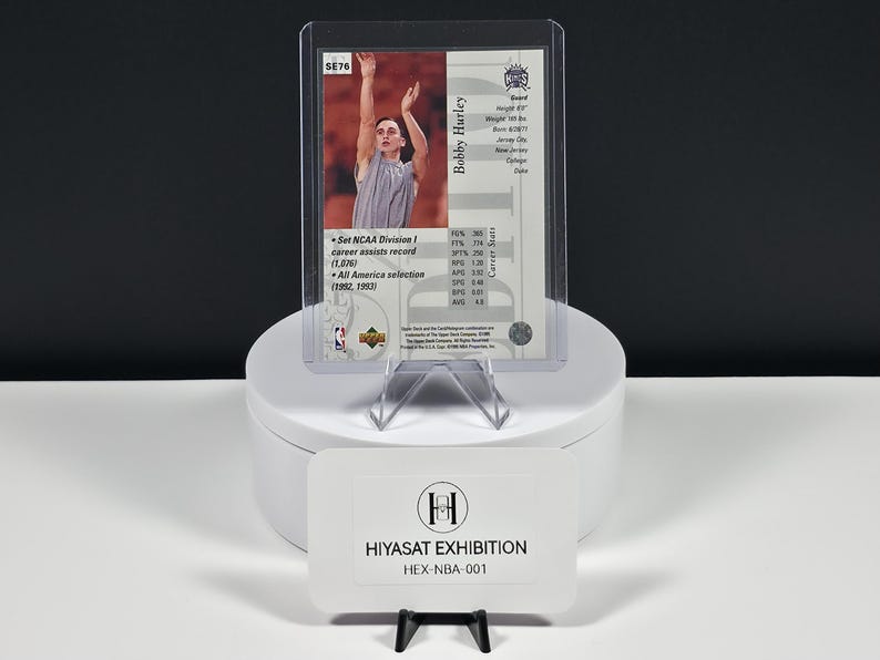 May include: A Bobby Hurley basketball trading card in a clear protective sleeve, featuring a photograph of the player shooting, career statistics, and the text Set NCAA Division I career assists record (1,076). Includes a Hiyasat Exhibition card.