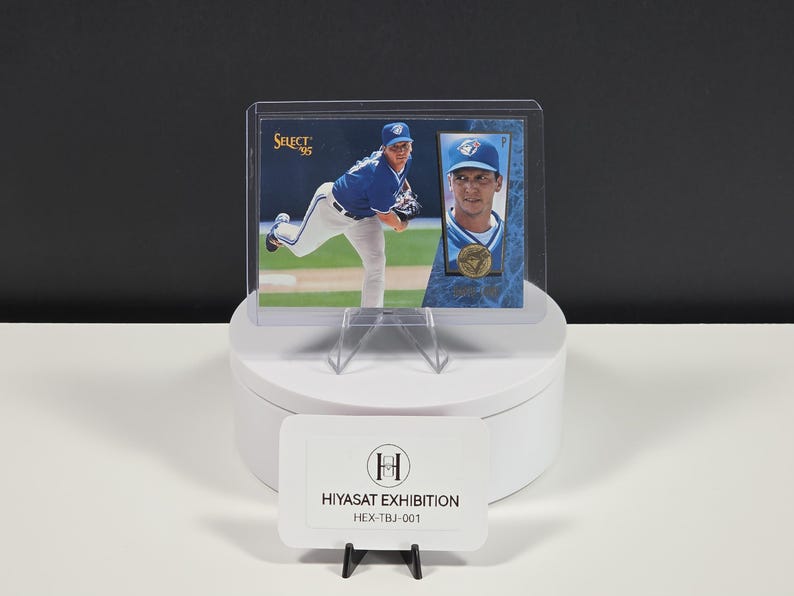 Puede incluir: Una tarjeta de b&eacute;isbol Select 95 que muestra a un jugador con uniforme azul y blanco, dentro de un protector de pl&aacute;stico transparente. La tarjeta presenta una foto de acci&oacute;n de cuerpo completo y un retrato, con un emblema circular dorado y el texto HIYASAT EXHIBITION.