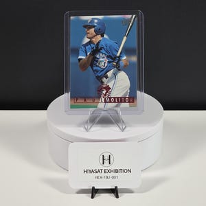 Puede incluir: Una tarjeta de b&eacute;isbol que muestra a Paul Molitor con un uniforme azul de los Toronto Blue Jays, sosteniendo un bate. La tarjeta est&aacute; dentro de una funda protectora de pl&aacute;stico transparente y muestra el nombre PAUL MOLITOR en una franja roja.