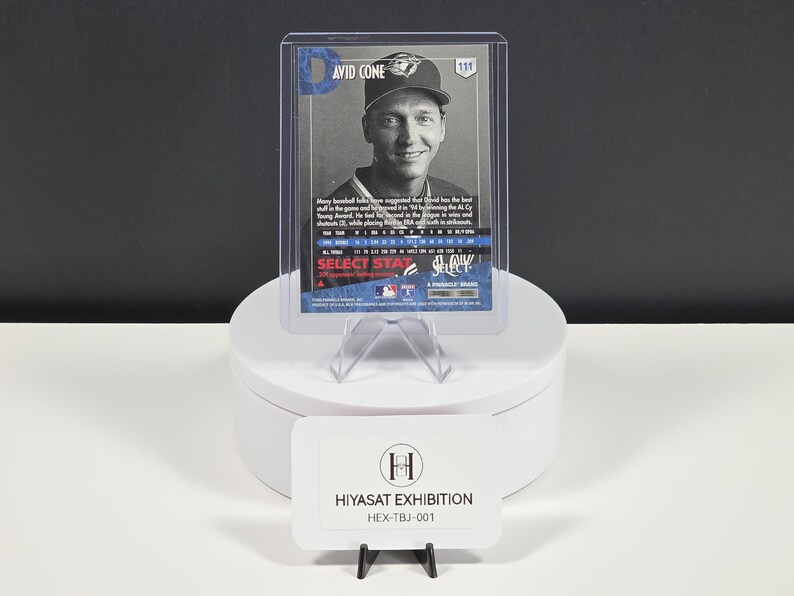 Puede incluir: Una tarjeta de b&eacute;isbol de David Cone en una funda protectora de pl&aacute;stico transparente. La tarjeta presenta un retrato en blanco y negro del jugador, texto azul y estad&iacute;sticas. Un letrero rectangular blanco con la etiqueta HIYASAT EXHIBITION HEX-TBJ-001 se encuentra debajo.