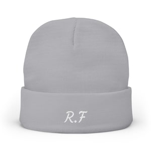 Può includere: Un berretto in maglia grigio chiaro con risvolto. Sulla parte anteriore del risvolto sono ricamate in bianco le lettere R.F con un carattere stilizzato e leggermente testurizzato. Il berretto presenta una classica forma a corona arrotondata.
