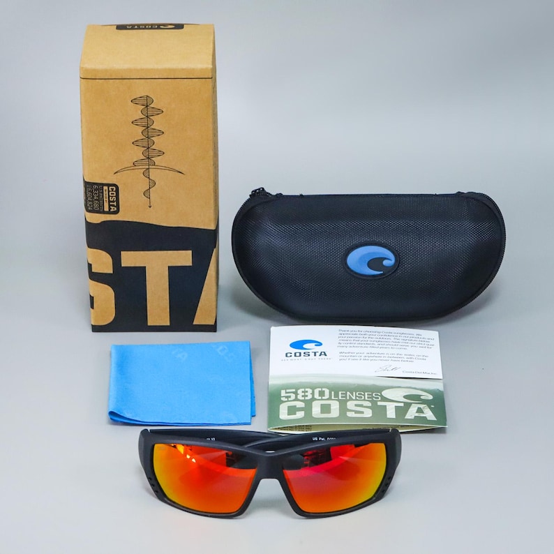 Puede incluir: Gafas de sol Costa con montura negra mate y lentes naranjas reflectantes, acompa&ntilde;adas de un estuche r&iacute;gido negro con cremallera, un pa&ntilde;o de limpieza de microfibra azul claro, una caja de cart&oacute;n Costa y un folleto informativo 580 lenses.