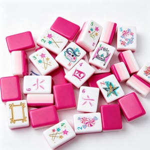 May include: A collection of rectangular mahjong tiles in shades of pink and white. The tiles feature various illustrations including pink and teal wands with stars, pink candies, a gold frame, a stylized star, and Chinese characters in pink ink.