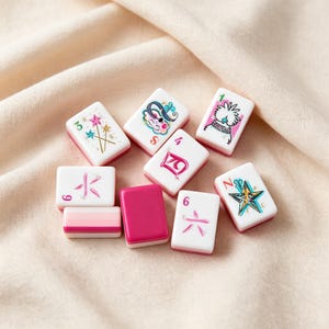 May include: A collection of nine rectangular mahjong tiles with white faces and magenta backs. The tiles feature various colorful illustrations including stars, a stylized character, and Chinese numerals in pink and teal ink on the white surfaces.