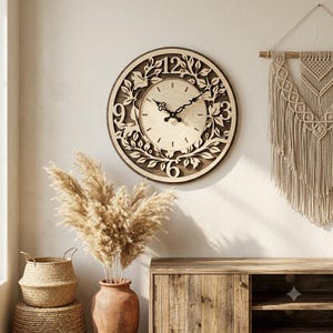 Può includere: Un orologio da parete circolare con quadrante in legno chiaro, lancette nere decorate e cornice in legno scuro. Il quadrante è circondato da un bordo decorativo in legno tagliato al laser con motivi di foglie e viti e grandi numeri.