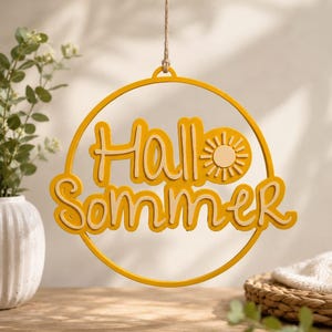 Könnte beinhalten: Ein rundes, gelbes Hängeschild mit dem Schriftzug "Hallo Sommer" in einer geschichteten Schreibschrift. Das Design enthält ein kleines Sonnensymbol neben dem Text, alles eingefasst in einen dünnen gelben Kreisrahmen, der an einer Schnur hängt.