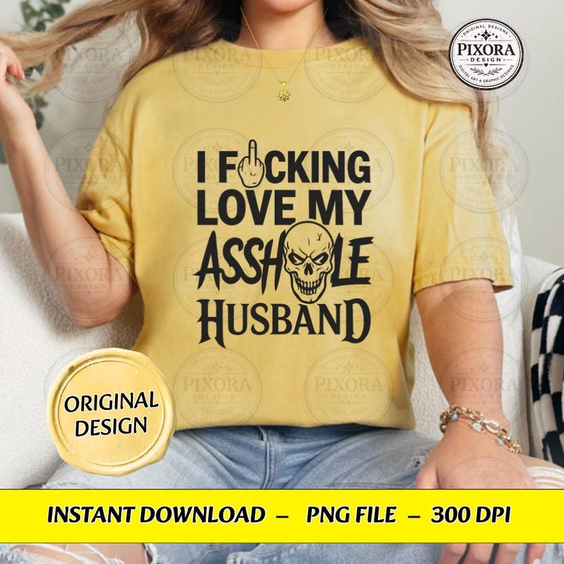 May include: A mustard yellow short-sleeve t-shirt featuring black text that reads I FUCKING LOVE MY ASSHOLE HUSBAND. The design includes a graphic of a hand making a middle finger gesture and a skull illustration replacing the letter O in ASSHOLE.