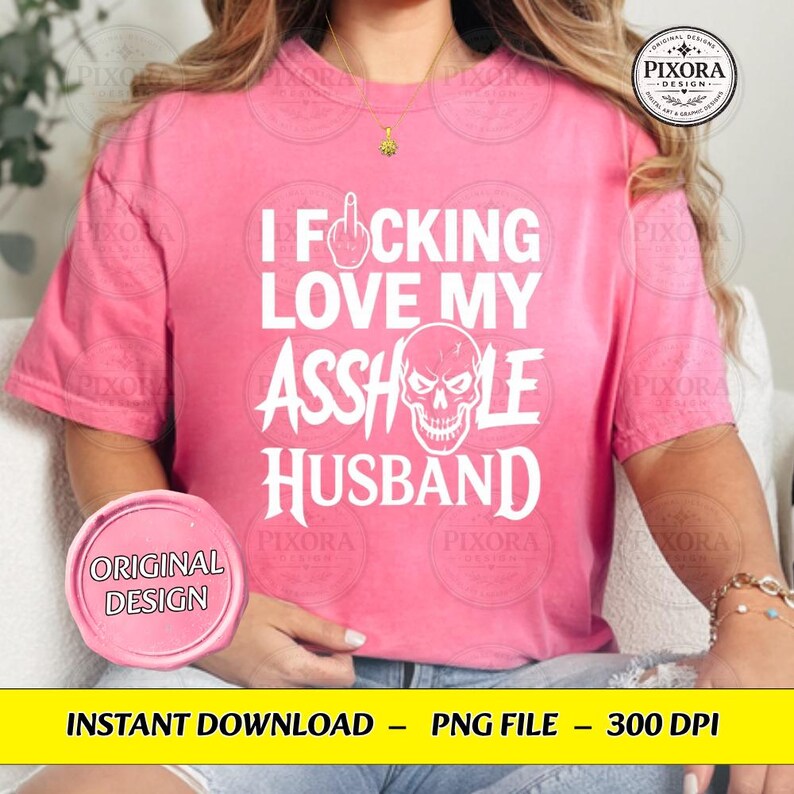 May include: A bright pink short-sleeved t-shirt featuring white text that reads I FUCKING LOVE MY ASSHOLE HUSBAND, with a graphic of a middle finger replacing the letter U and a skull illustration replacing the letter O in the word ASSHOLE.