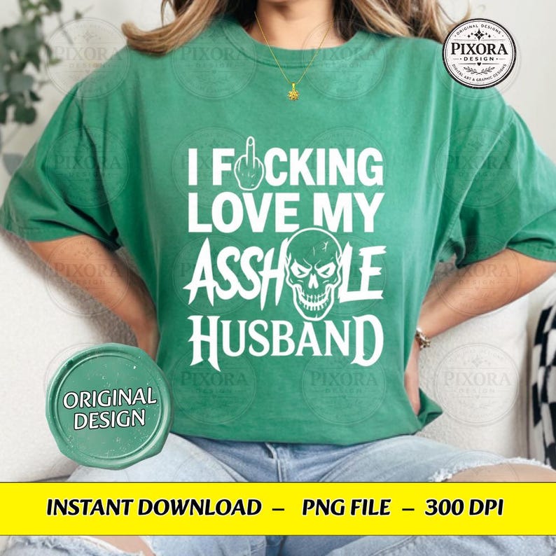 May include: A green short-sleeve t-shirt featuring white text that reads I FUCKING LOVE MY ASSHOLE HUSBAND, with a graphic of a middle finger replacing the letter U and a skull illustration replacing the letter O in the word ASSHOLE.