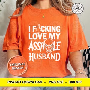 May include: An orange short-sleeved t-shirt featuring white text that reads I FUCKING LOVE MY ASSHOLE HUSBAND with a graphic of a middle finger icon replacing the letter U and a skull illustration replacing the letter O in the word ASSHOLE.