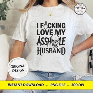 May include: A white short-sleeve t-shirt featuring black text that reads I FUCKING LOVE MY ASSHOLE HUSBAND, with a middle finger icon replacing the letter U and a skull graphic replacing the letter O in the word ASSHOLE.