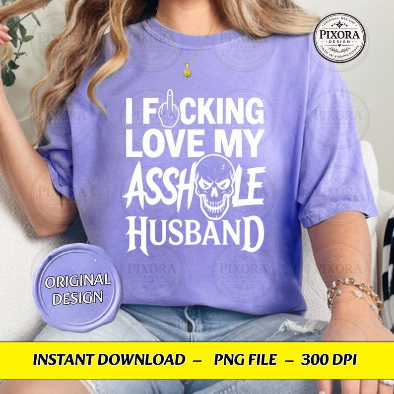 May include: A light purple short-sleeve t-shirt featuring white text that reads I FOCKING LOVE MY ASSHOLE HUSBAND, with a middle finger icon replacing the O in FOCKING and a white skull graphic integrated into the word ASSHOLE.
