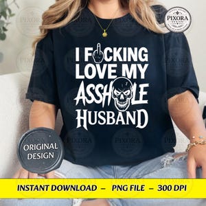 May include: A black short-sleeved t-shirt featuring white text that reads I FUCKING LOVE MY ASSHOLE HUSBAND, with a graphic of a middle finger replacing the letter U and a skull illustration replacing the letter O in the word ASSHOLE.