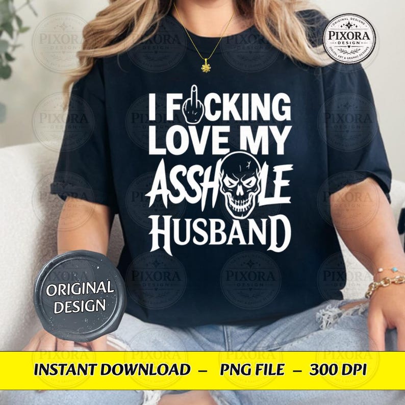 May include: A black short-sleeved t-shirt featuring white text that reads I FUCKING LOVE MY ASSHOLE HUSBAND, with a graphic of a middle finger replacing the letter U and a skull illustration replacing the letter O in the word ASSHOLE.