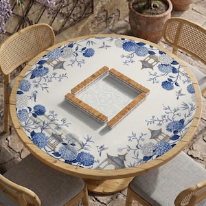 May include: A round table cover featuring a white background with a blue floral pattern, including hydrangea clusters, small birds, and pagoda illustrations. In the center, a square frame is constructed from light brown wooden tiles.